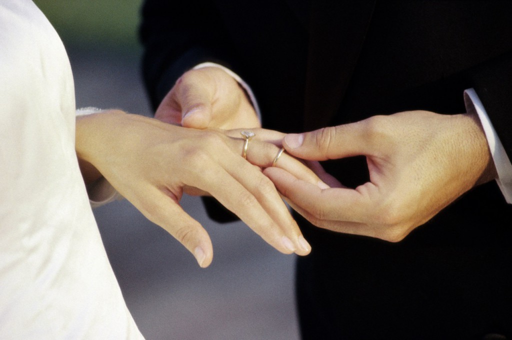 Close-up of a groom placing a ring on his bride's finger